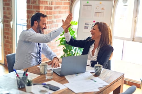 Business woman and businessman giving each other a high five in a meeting